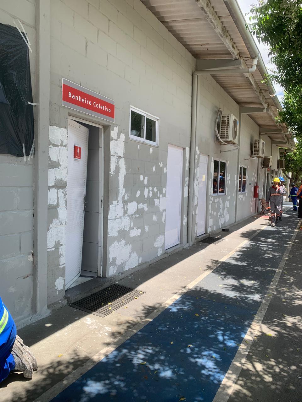 Fachada de edifício em manutenção, com profissionais usando capacete e uniforme refletivo